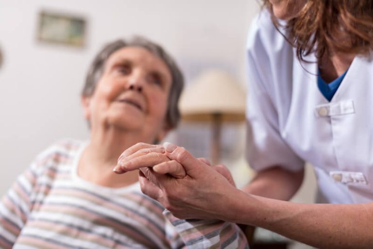 Une ifirmière en Ehpad prenant soin de sa patiente âgée.