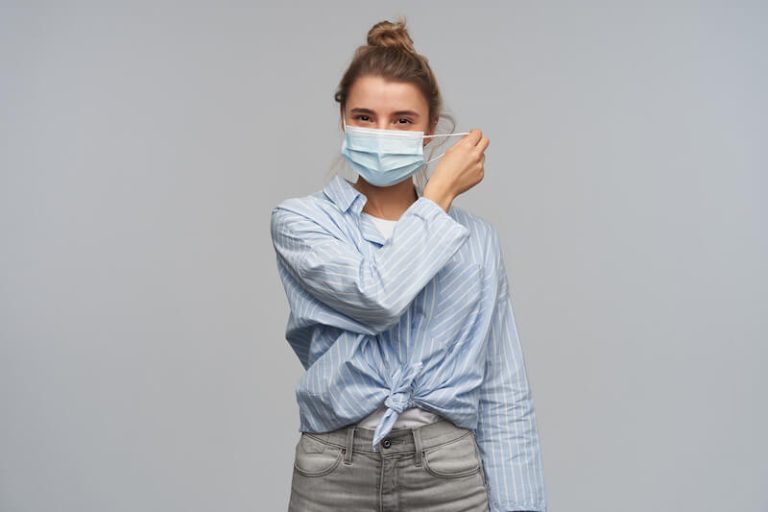Une jeune fille enlève son masque anti Covid-19.