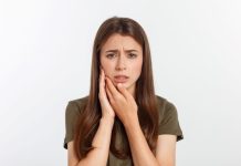 Une jeune femme souffrant des dents : parodontite ou carie.