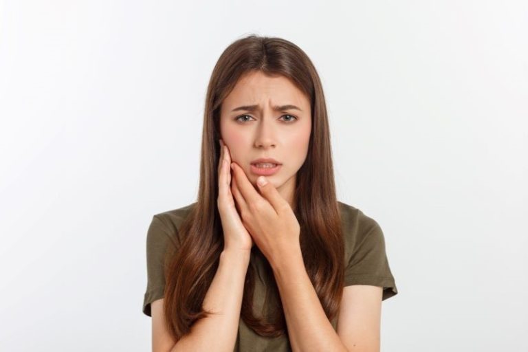 Une jeune femme souffrant des dents : parodontite ou carie.