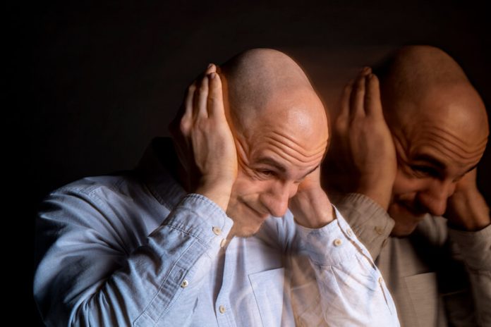 Un homme atteint par la schizophrénie se bouche les oreilles