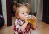 une petite fille boit du soda dans un biberon