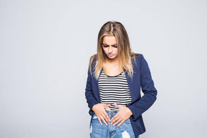Une femme victime d'une infection au papillmoavirus tient le bas de son ventre.