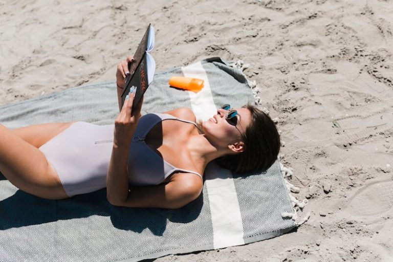 Une femme bronze au soleil sur la plage.
