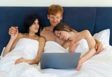 Deux jeunes femmes et un homme regardant du sexe sur un écran.