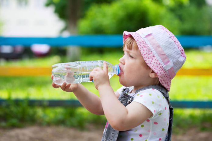 Un enfant en bas âge consomme de l'eau afin de prévenir la déshydratation.