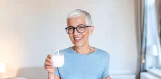 Femme senior buvant un verre de lait riche en calcium.