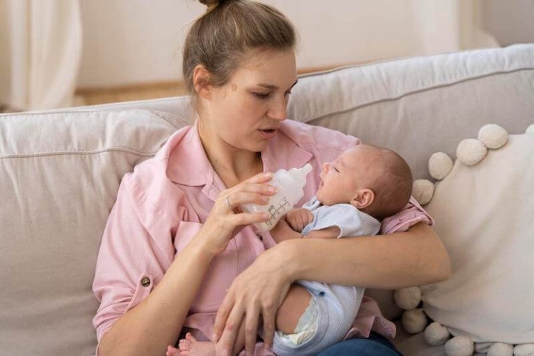Un bébé prend son biberon dans les bras de sa maman, inquiète de son probable reflux.