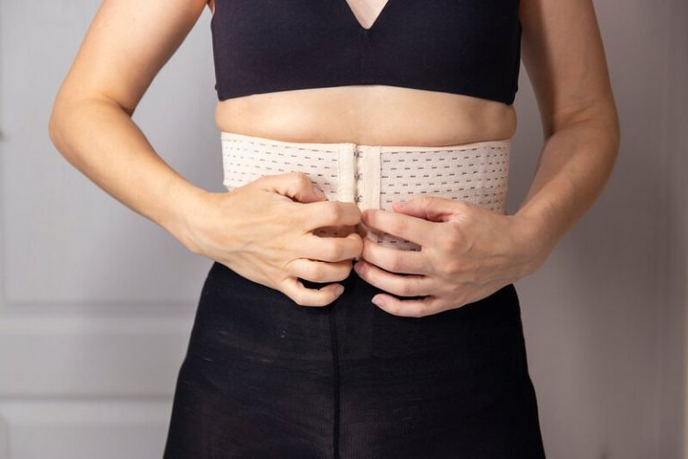 Femme avec une ceinture post-accouchement qui se touche le ventre.