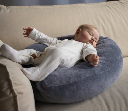 Un cocon pour bébé en bord de canapé avec un enfant en train de dormir dessus.