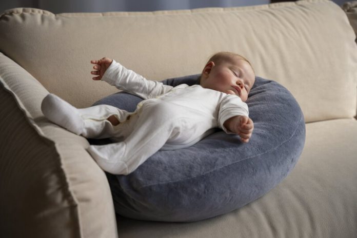 Un cocon pour bébé en bord de canapé avec un enfant en train de dormir dessus.