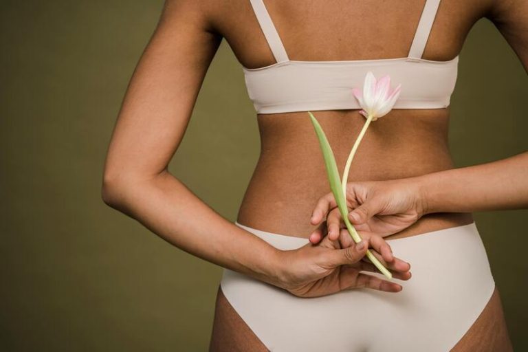 Une femme atteinte de cellulite porte une culotte de cheval et tient une fleur.
