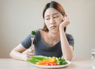 Une femme qui mange des légumes avec dégoût qu'elle a du cholestérol.