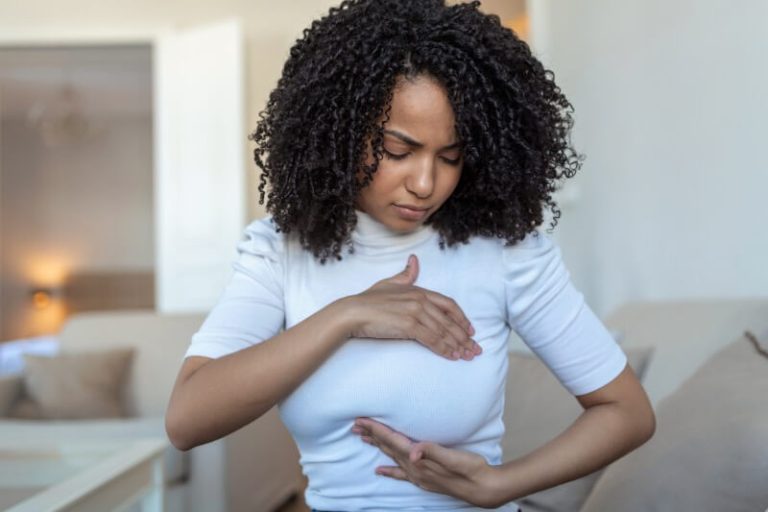 Femme examinant sa poitrine, suspectant le développement de seins dits tubéreux.