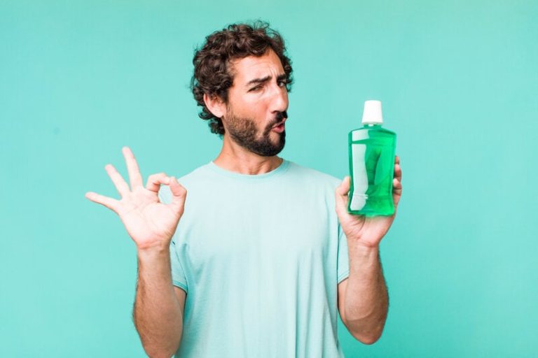 Homme très satisfait qui tient une bouteille de bain de bouche à base bicarbonate de sodium.
