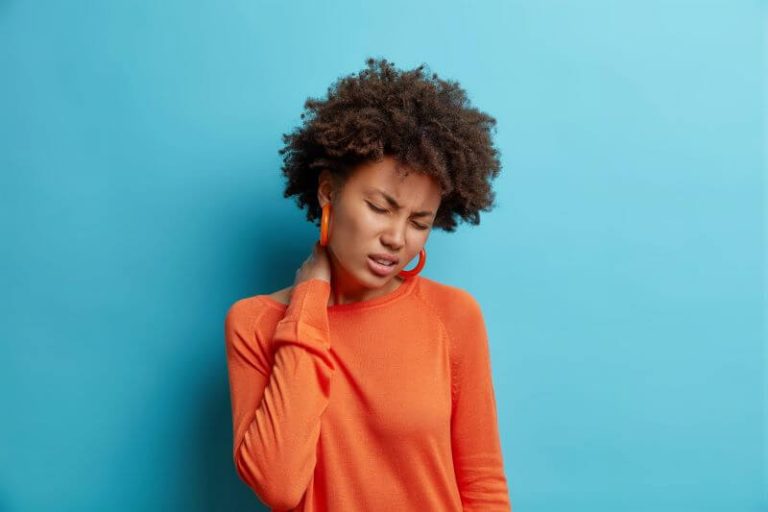 Une femme se tient la nuque à cause de douleurs musculaires persistantes.