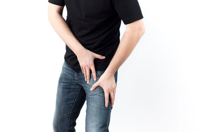 Un homme qui se tient la cuisse à cause de la douleur liée à une cruralgie.