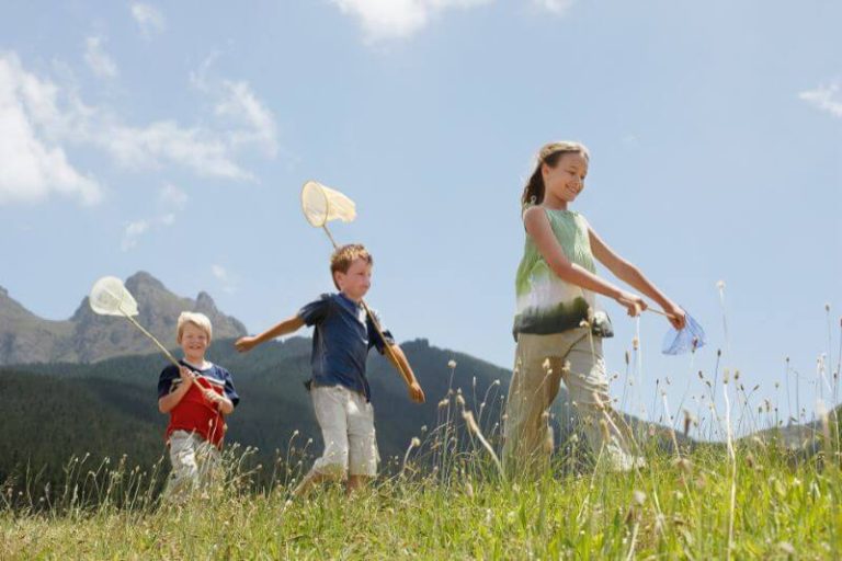 des enfants qui jouent dans des herbes hautes, inconscient de la présence de certains nuisibles comme les tiques.
