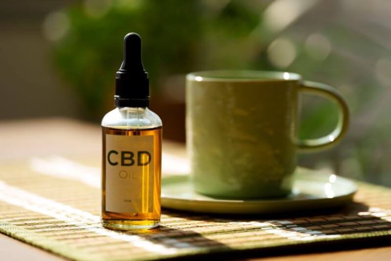 Une huile de cannabidiol (CBD) près d'une tasse de thé.