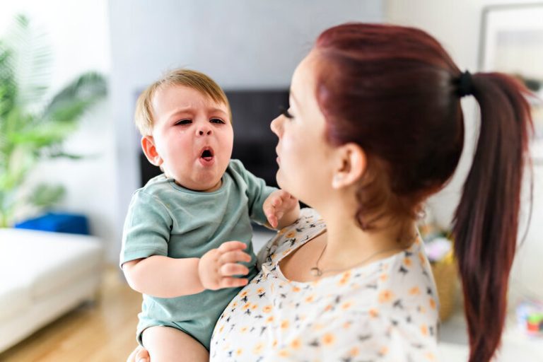 Une mère tenant son enfant qui tousse à cause de la coqueluche.