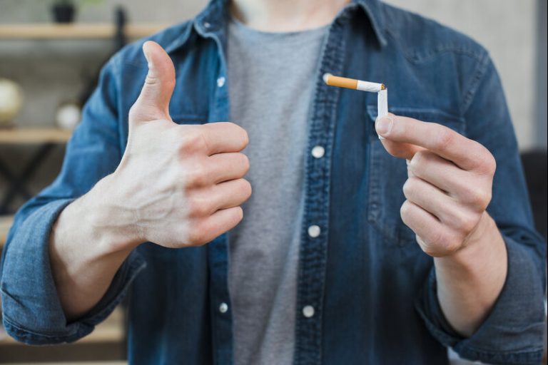 Un homme heureux qui tient une cigarette cassée dans sa main.