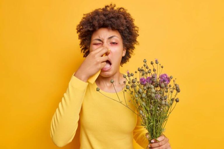 Une femme se bouche le nez à cause de son allergie au pollen contenu dans le bouquet.