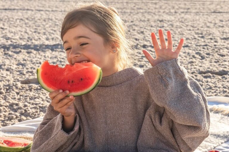 Une jeune fille déguste une tranche de pastèque juteuse sous le soleil.