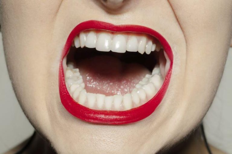 Les dents d'une femme arborant un rouge à lèvres éclatant.