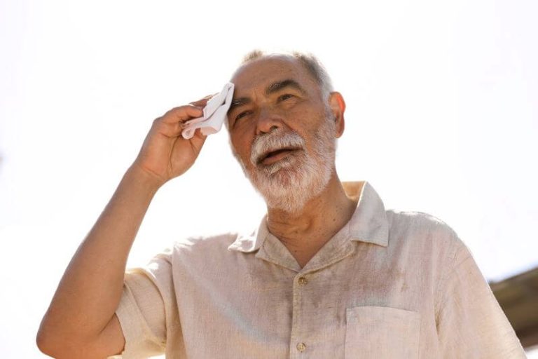 Un senior s'essuie le cuir chevelu, exposé à la chaleur du soleil.