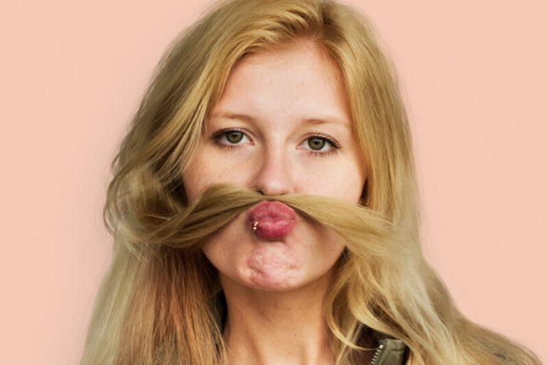 Une femme fait une imitation de moustache avec ses cheveux.
