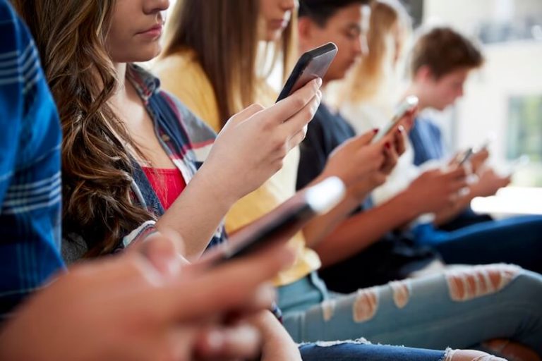 Des collégiens en train de consulter leur smartphone dans leur établissement.