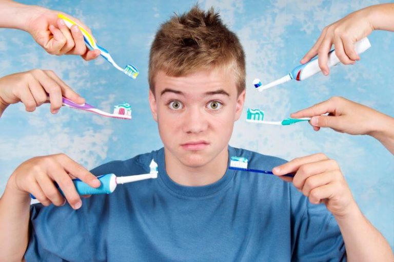 Un garçon fait une grimace, entouré de brosses à dents.