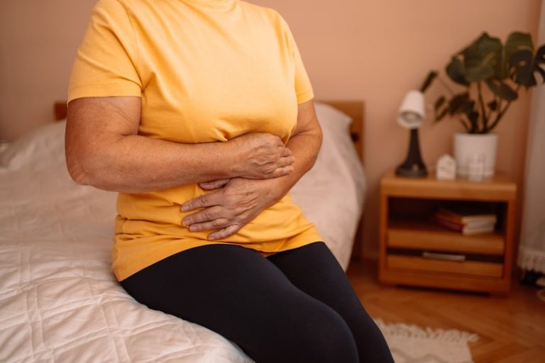 Une personne âgée qui se tient le ventre parce qu'elle a des maux de ventre liés à un cancer de l'estomac.