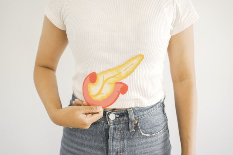 Une femme qui tient une image de pancréas au niveau du ventre pour montrer ce que c'est et où il se situe.