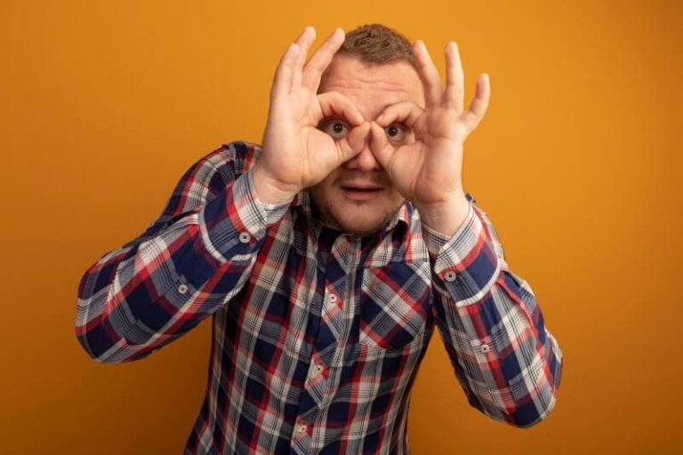 Un homme mime le port de lunettes en utilisant ses mains.