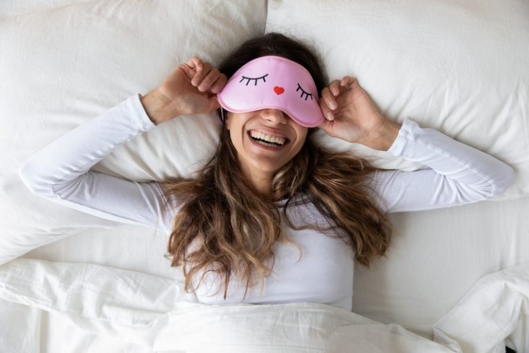 Une femme dans son lit en train de se coucher avec un masque appliquant les conseils pour bien dormir.