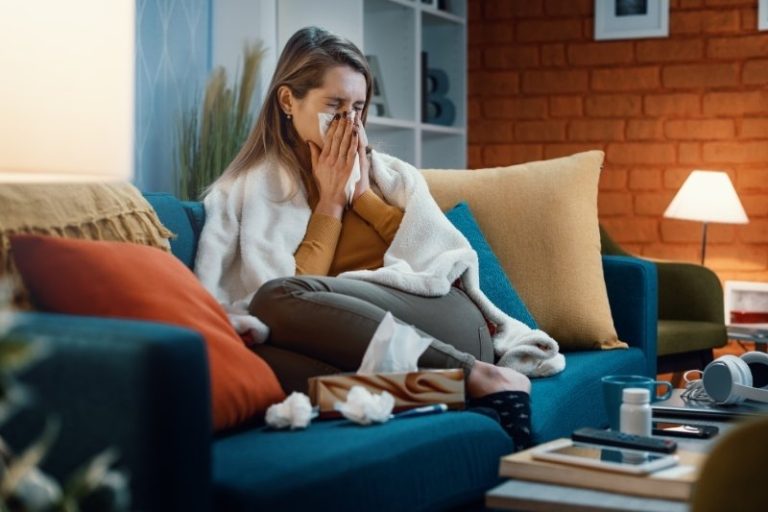 Une femme se mouche sur son canapé.