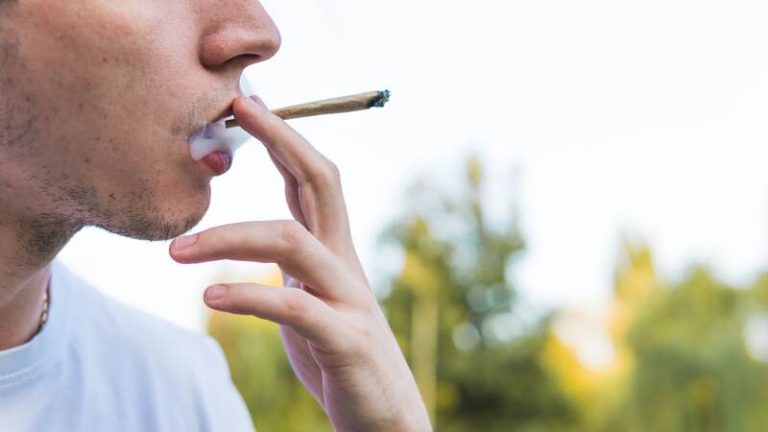 Un homme en train de fumer un joint de cannabis.
