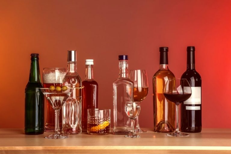 Une lignée de bouteilles de différents alcools sur une table.