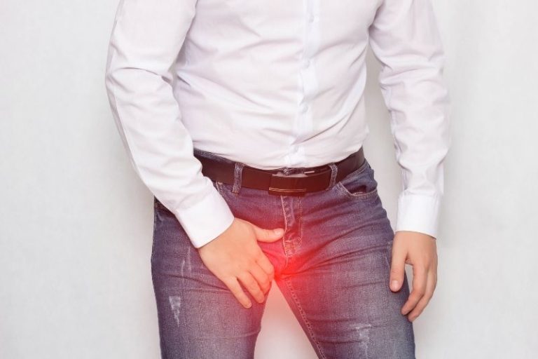 Un homme se tient les testicules à cause d'une douleur vive.