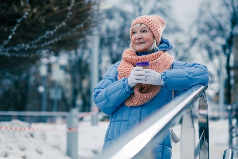 Une femme dehors dans le froid, en pleine forme, avec une tasse à café chaude.