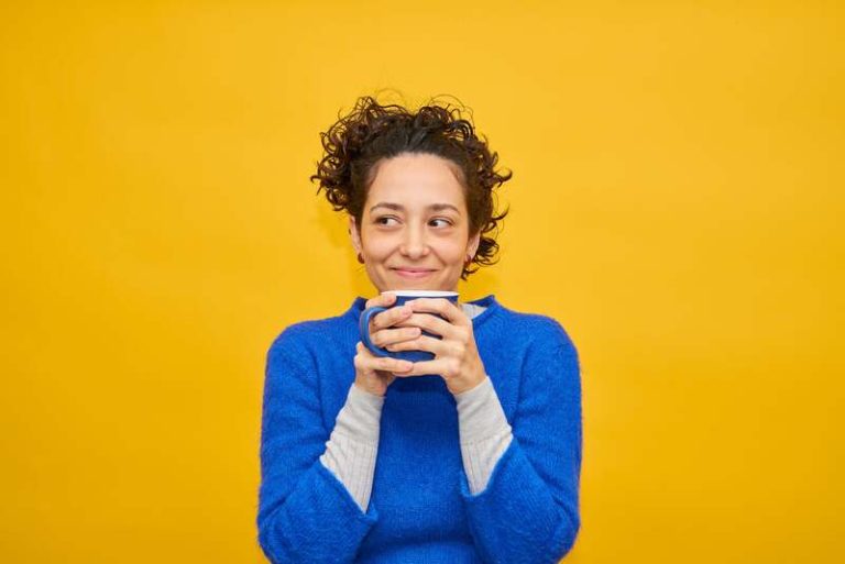 Une femme souriante qui a bu plusieurs cafés dans la même tasse toute la journée.