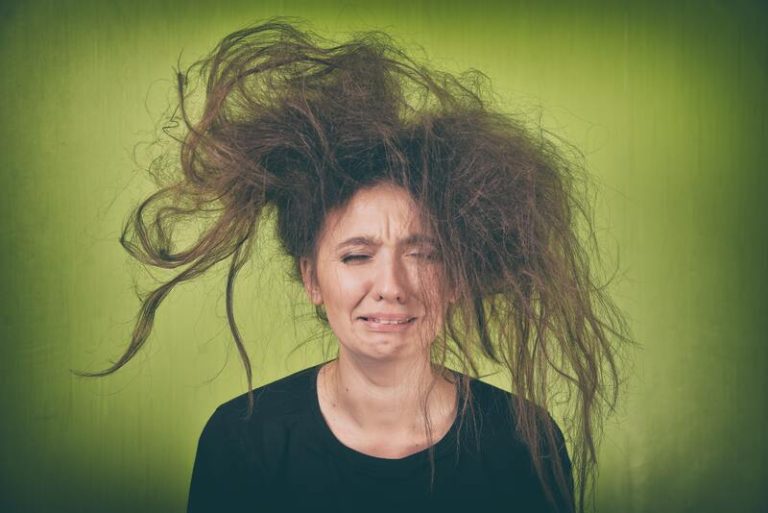 Une femme ayant les cheveux fins essaye, en vain, de les coiffer pour avoir du volume.