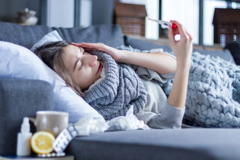 Une femme malade, affalée sur un canapé avec des médicaments et un thermomèrre. Une femme malade, affalée sur un canapé avec des médicaments et un thermomèrre. Une femme malade, affalée sur un canapé avec des médicaments et un thermomètre. Une femme malade, affalée sur un canapé avec des médicaments et un thermomètre.