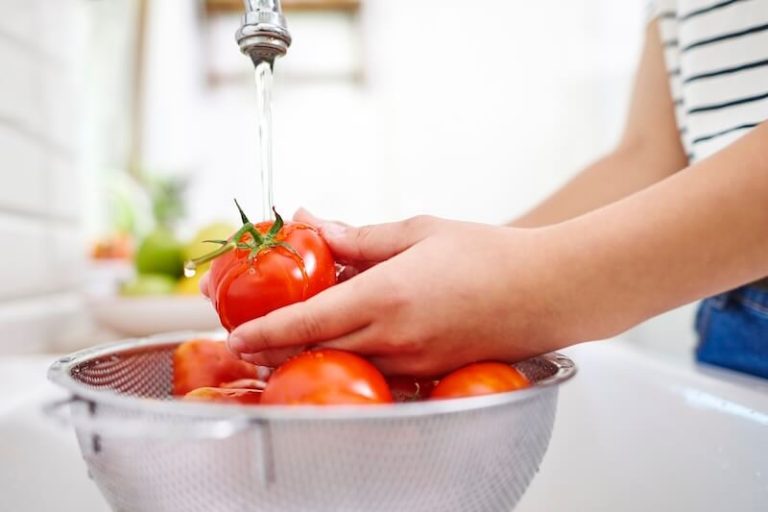 Une cuisinière rince ses tomates à l'eau claire.