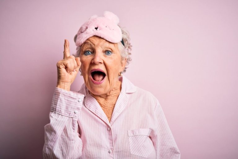 Une vieille dame en pyjama avec un masque de nuit.
