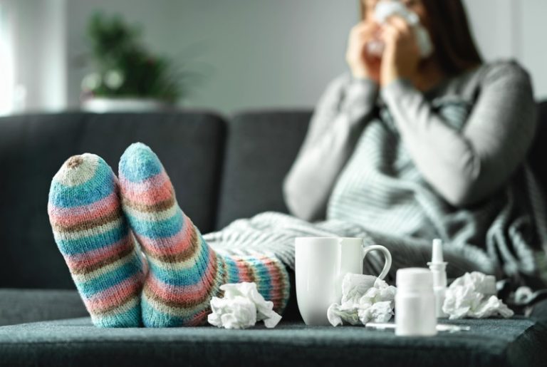 Une femme qui a attrapé la grippe et qui essaie de se soigner.