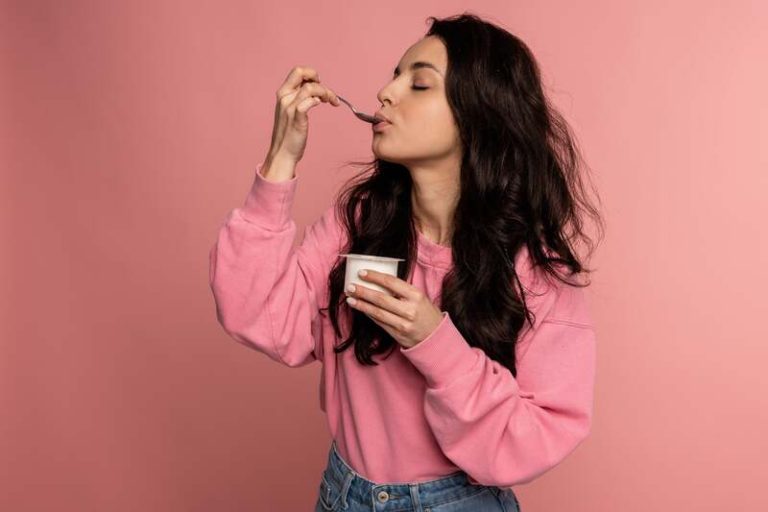 Une femme qui mange un yaourt riche en calcium pour diminuer les risques de cancer colorectal.