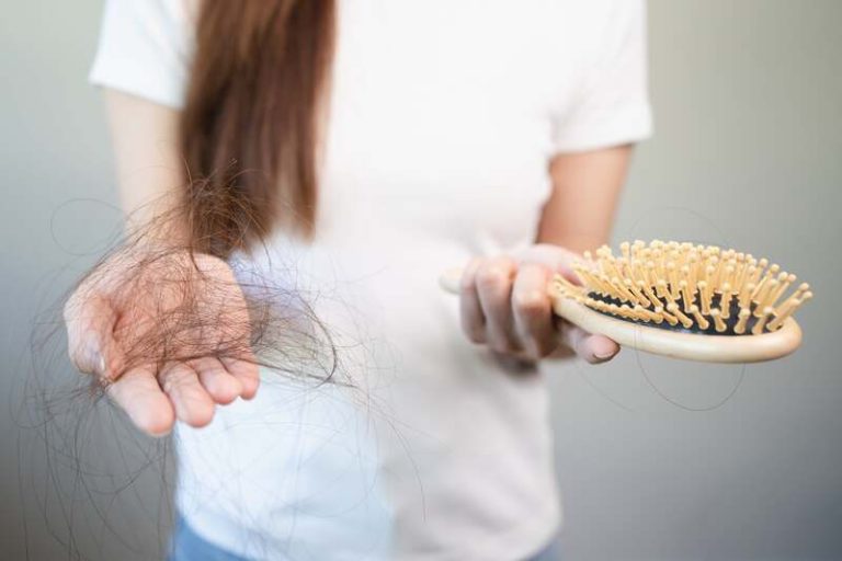 Une femme qui décroche de sa brosse à cheveux tous les cheveux qu'elle a perdus.
