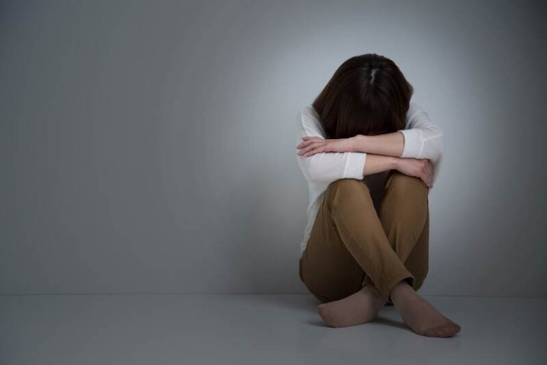 Une femme atteinte de dépression, recroquevillée sur elle-même.